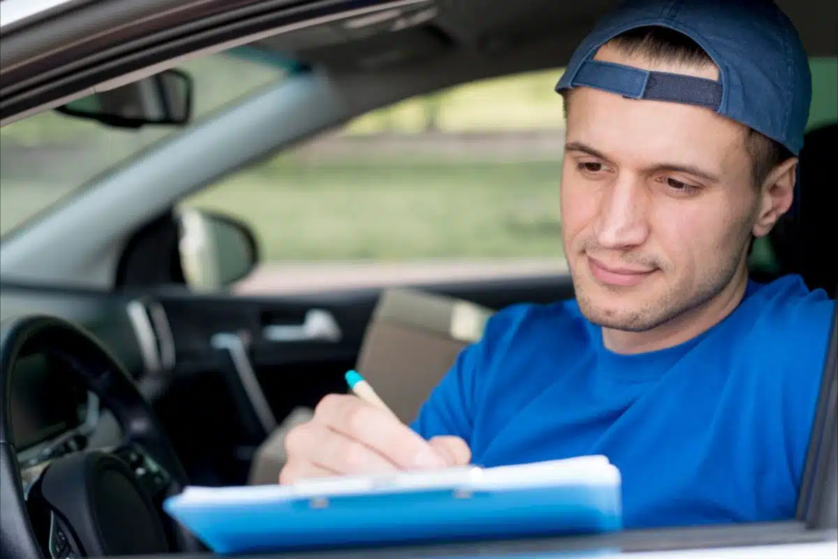 Young man filling out form in car
