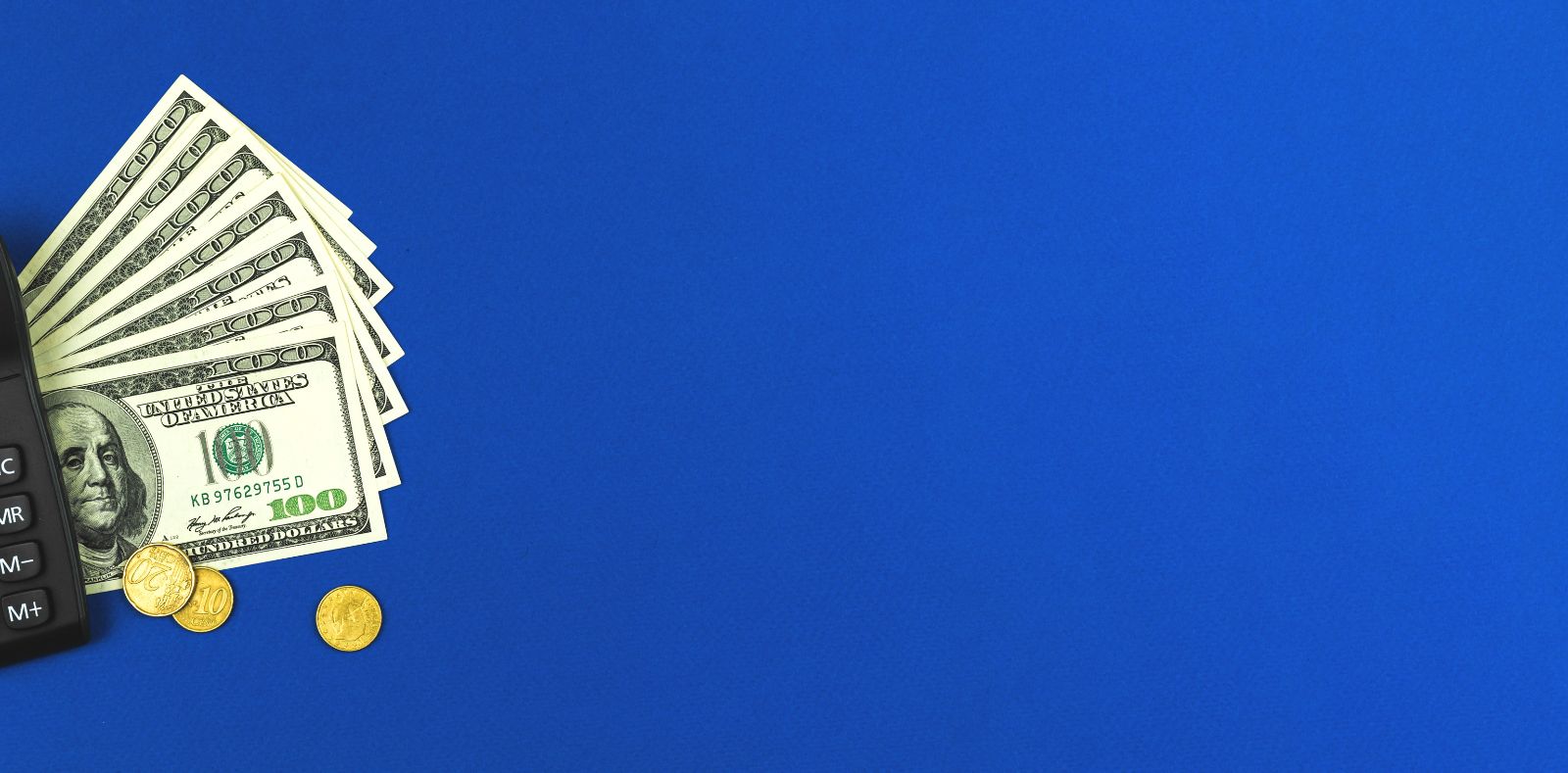 A man in a navy shirt extends a fanned bundle of dollar bills toward the camera in a blurred modern interior with plants and a computer desk
