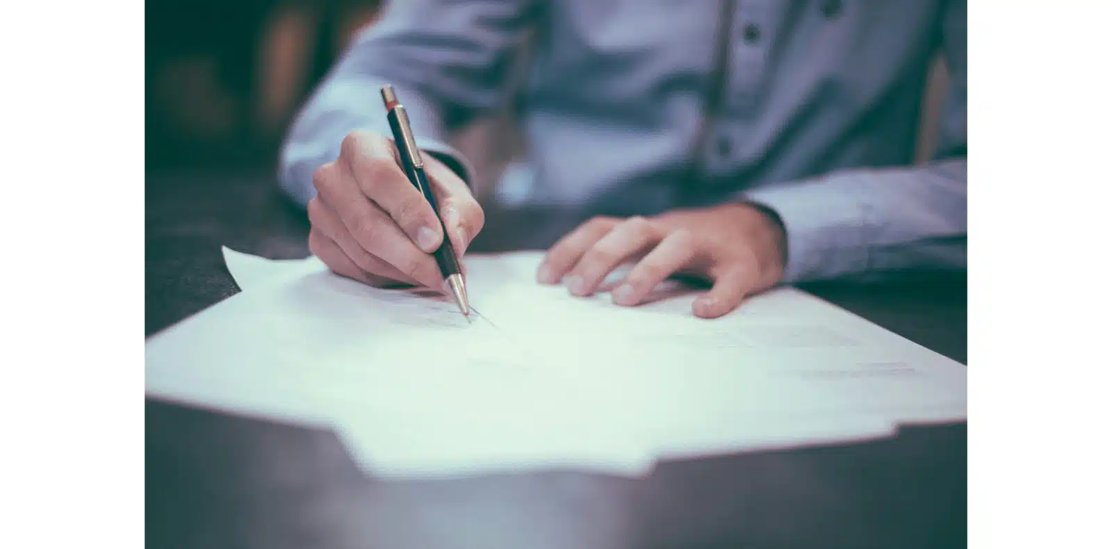 Person signing a financial agreement document, representing loan approval or credit contract.